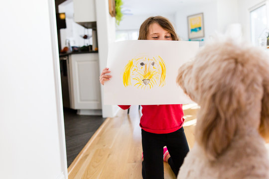 Girl showing crayon drawing to dog