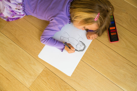 Overhead view of girl on floor drawing in drawing pad