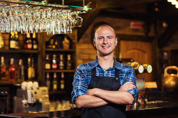 Barman at work in pub,Portrait of cheerful barman worker standing,Waiter giving menus,A pub.Bar.Restaurant.Classic.Evening.European restaurant.European bar.American restaurant.American bar.
