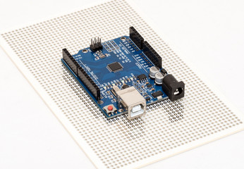 Arduino Uno compatible micro-controller development board positioned over prototyping PCB plate
