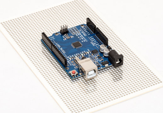 Arduino Uno compatible micro-controller development board positioned over prototyping PCB plate
