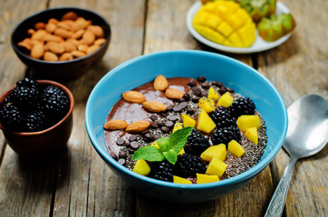 Chocolate smoothies breakfast bowl with chocolate chips, mango, blackberry, almond and Chia seeds. toning. selective focus