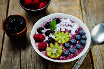 Blueberry smoothies breakfast bowl with coconut flakes, raspberry, blueberry and blackberry