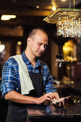 Barman at work in pub,Portrait of cheerful barman worker standing,Waiter giving menus,A pub.Bar.Restaurant.Classic.Evening.European restaurant.European bar.American restaurant.American bar.