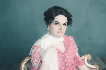 Transgender woman vintage 1920s fashion sitting on sofa.