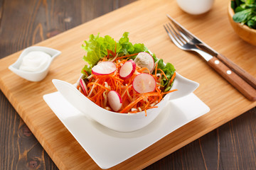 vegetable salad on a white plate, wooden board and background.