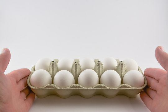 Hands hold a box of white eggs isolated