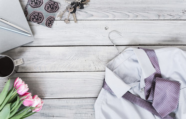 Fragment of a men's shirt with a tie on a hanger, tulips, coffee