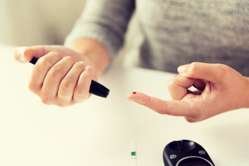 close up of woman making blood test by glucometer