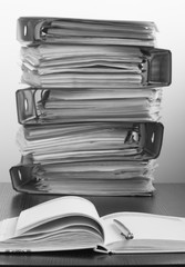 Five folders with documents stacked in a pile on the table. Blac