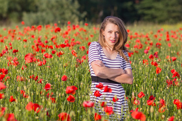 Naklejka na ściany i meble Smiling young woman on poppy field
