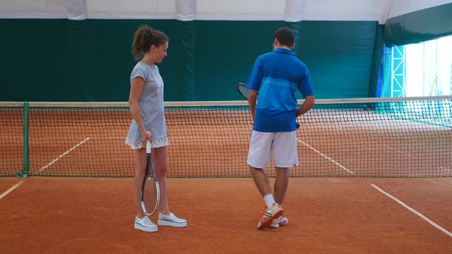 The coach training beautiful girl on tennis court