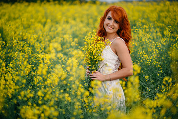 Naklejka na ściany i meble Young red-haired woman in a rapeseed field