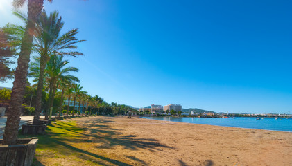 Ibiza sun shines of the beach in Sant Antoni de Portmany,  Take a walk along main boardwalk or in the sand.   November beach in warm morning sunshine. 