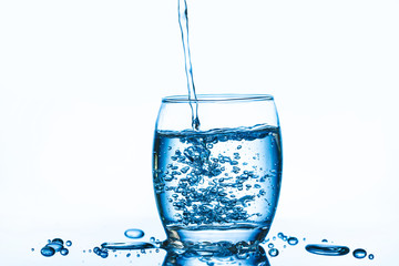 Pouring mineral water into transparent glass isolated on white.