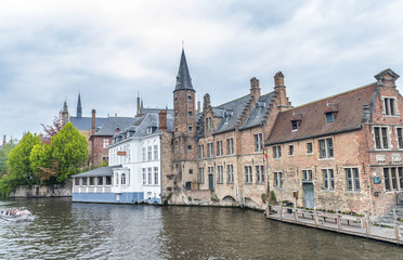 Fototapeta na wymiar BRUGES, BELGIUM - MARCH 2015: Tourists visit ancient medieval city on a cloudy day. Brugge attracts more than 2 million people annually