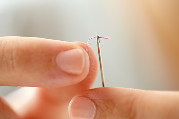 hands of tailor woman threading needle