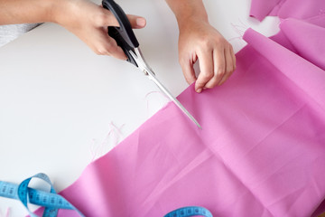woman with tailor scissors cutting out fabric