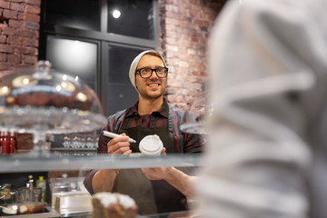 man or barman with coffee cup and customer at cafe