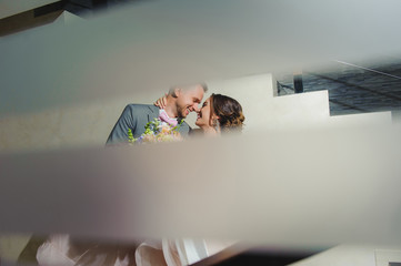 Portrait of a Happy newlyweds indoors. Bride and groom smiling. Bouquet in hand.