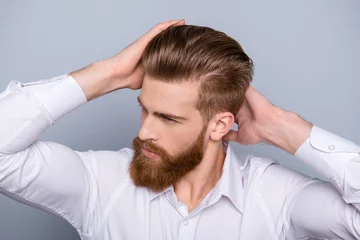 Photo sur Plexiglas Salon de coiffure Portrait of confident man with red beard touching his hair