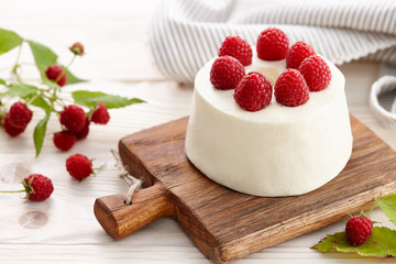 Raspberry mousse cake with fresh raspberries on wooden board