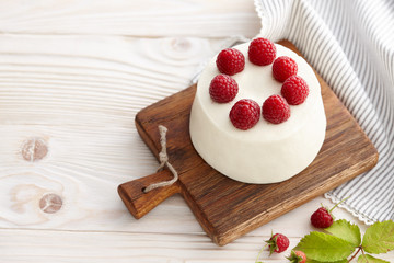 Raspberry mousse cake with fresh raspberries on wooden board
