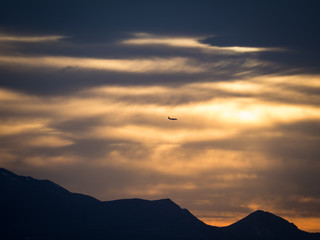 plane descending over mountains at sunset