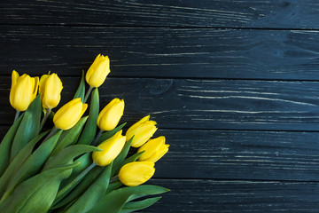 Bouquet of yellow tulips isolated on a black wooden background