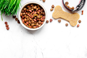 dry dog food in bowl on stone background top view
