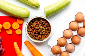 Dogfood set with vegetables, eggs and meat on table background top view