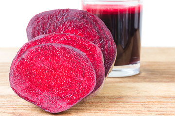 Obraz na płótnie Canvas Cut half beetroot and fresh beet juice in glass on wooden table, white background.