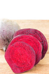 Cut slice beetroot on wooden table, white background.