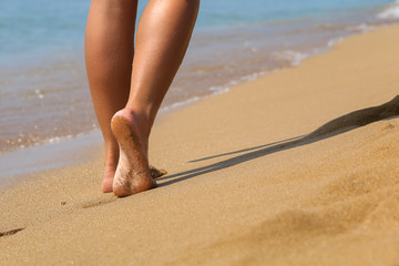 Young woman walking on the beach in the warm and sunny day