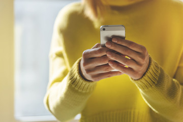 Close-up of female hands typing messages on modern smartphone, Happy smiling young girl using modern mobile phone while sunny day, Blurred background, flares effect.