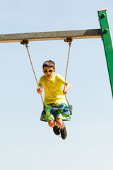 Boy playing swinging by swing-set.