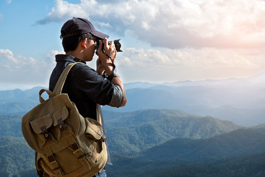Man Traveler with photo camera and backpack hiking outdoor Travel Lifestyle and Adventure concept.