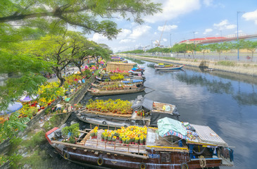 Fototapeta na wymiar Ho Chi Minh City, Vietnam - January 26, 2017: Flowers boats at flower market on along canal wharf. This is place where farmers sell apricot blossom and other flowers on Lunar New Year in Vietnam