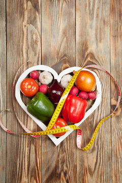 Sport and diet. Vegetables, centimeter. Peppers, tomatoes, garlic, onions,  radishes in the heart on rustic background