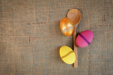Beautiful Easter egg design and wooden spoon over hessian texture background