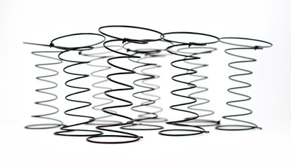 Group of Black Wire Springs used in Upholstery on white background with selective focus on the first spring.