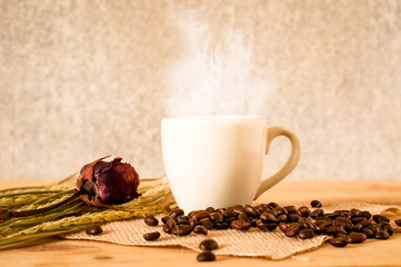 the hot coffee in the white cup on wooden table with coffee seed