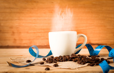the hot coffee in the white cup with blue measuring tape on wooden table and coffee seed. healthy and diet drink
