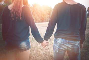 Fototapeta premium Lovers walk hand in hand on romantic evening sun, romantic atmosphere.