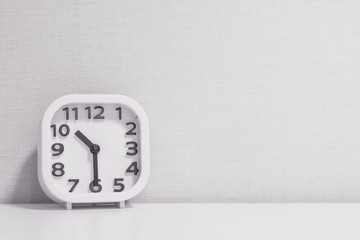 Closeup white clock for decorate show half past ten or 10:30 a.m. on white wood desk and cream...