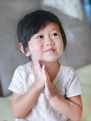 Portrait of cute little girl applying baby powder on her face. Talcum concept.
