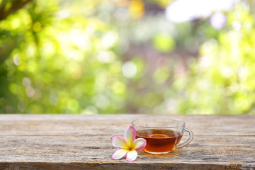 Obraz na płótnie Canvas Red tea and frangipani flower on wooden table