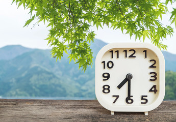 Closeup white clock for decorate show half past seven o'clock or 7:30 a.m. on blurred mountain view background