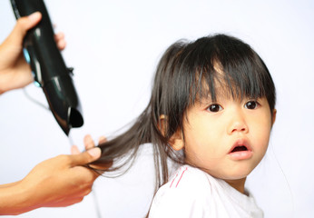 Mother drying hair of her child girl on white background
