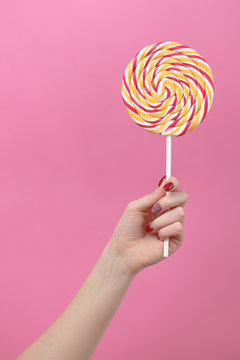 Female Hand Hold Lolipop On Pink Background